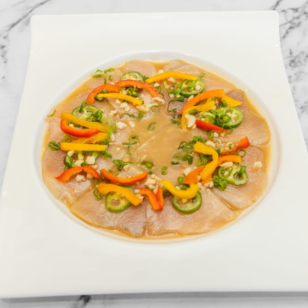 Yashima Restaurant's Japanese sashimi dish with sliced fish, peppers, and green onions in a light sauce.