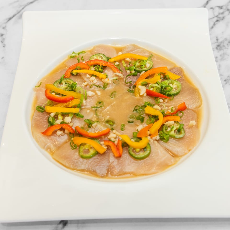 Yashima Restaurant's Japanese sashimi dish with sliced fish, peppers, and green onions in a light sauce.