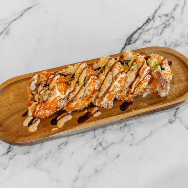 Yashima Restaurant's sushi roll with orange roe, avocado, and sauces on a wooden tray.