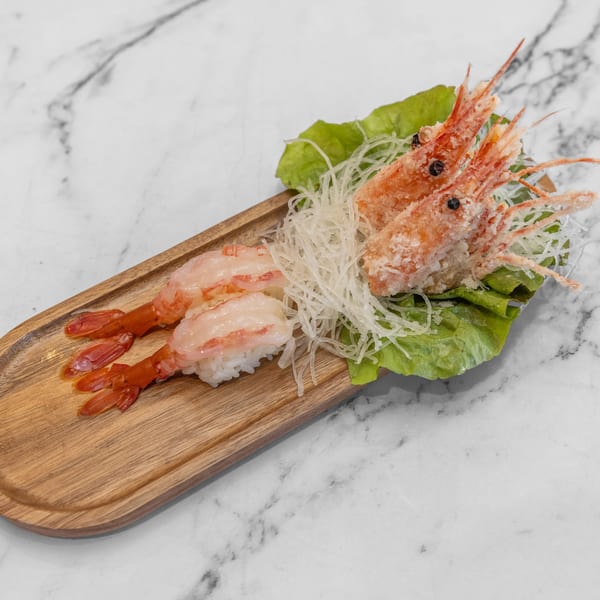 Yashima Restaurant's shrimp sushi and fried shrimp heads with shredded radish on a wooden board.