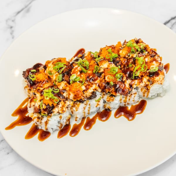 Yashima Restaurant's baked sushi roll, topped with orange roe, green onions, and a dark sauce drizzle.