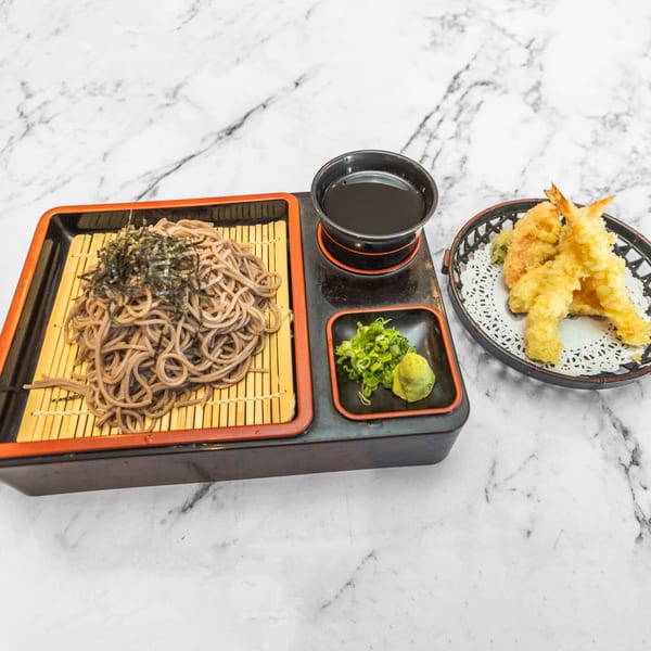 Japanese soba noodles with seaweed, tempura shrimp, dipping sauce, wasabi, and green onions.