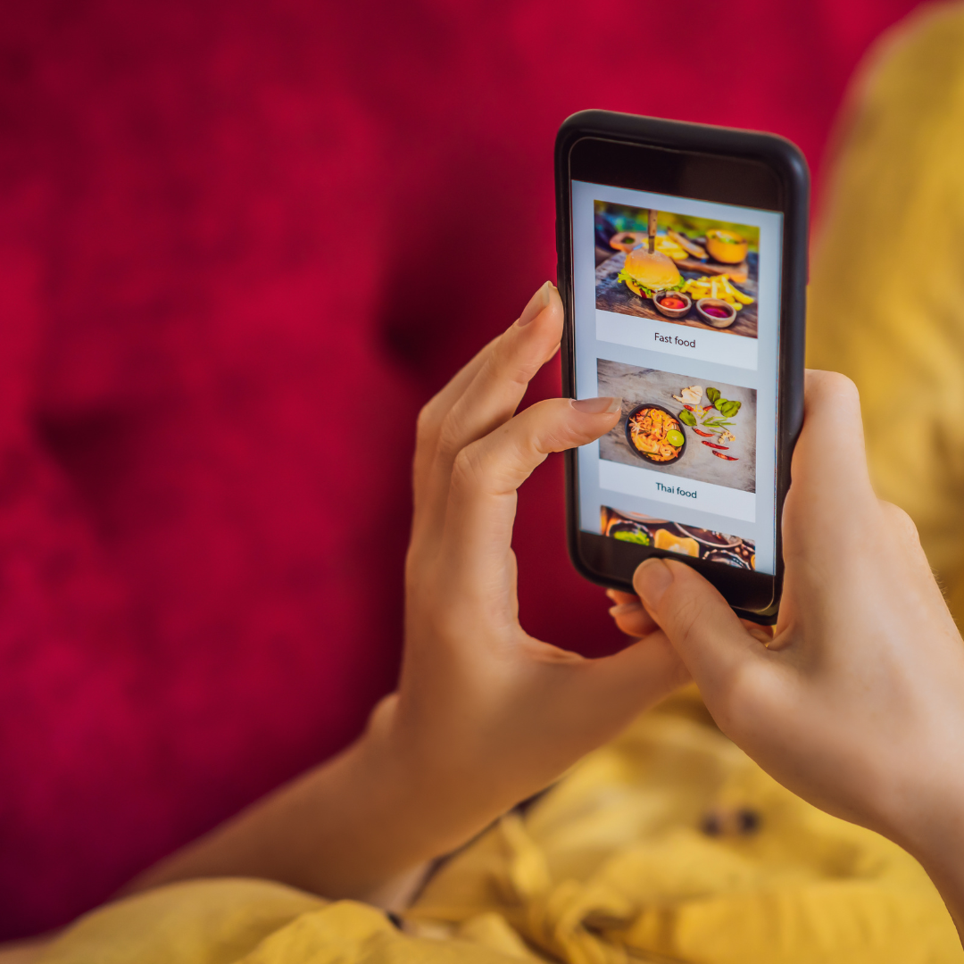 A person holding a phone with a food ordering app, with Japanese food in the background